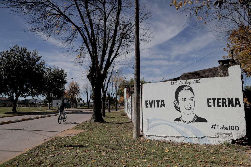 A man rides a bicycle near a mural of Eva Peron that reads in Spanish "Evita eternal" in Los Toldos, Argentina,Monday, May 6, 2019. One day ahead of the 100th anniversary of Evita's birth, the home where Argentina's mythical first lady was born and raised was opened to the public with an exhibition recounting the childhood of the woman who, together with her husband Juan Domingo Perón, will forever mark Argentine history. (AP Photo/Natacha Pisarenko)