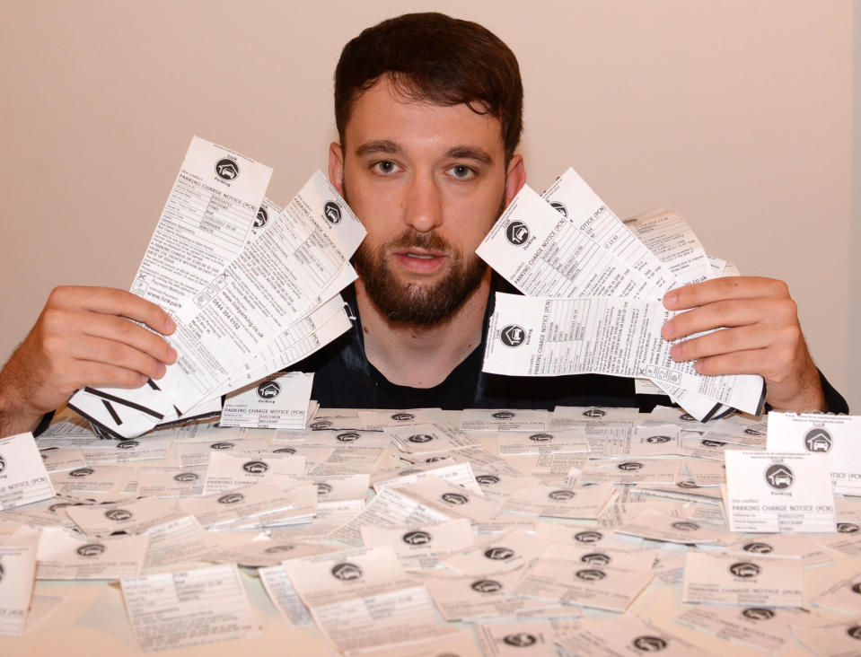 Konrad Koscinsci holds up just some of the couple’s many parking tickets (SWNS)