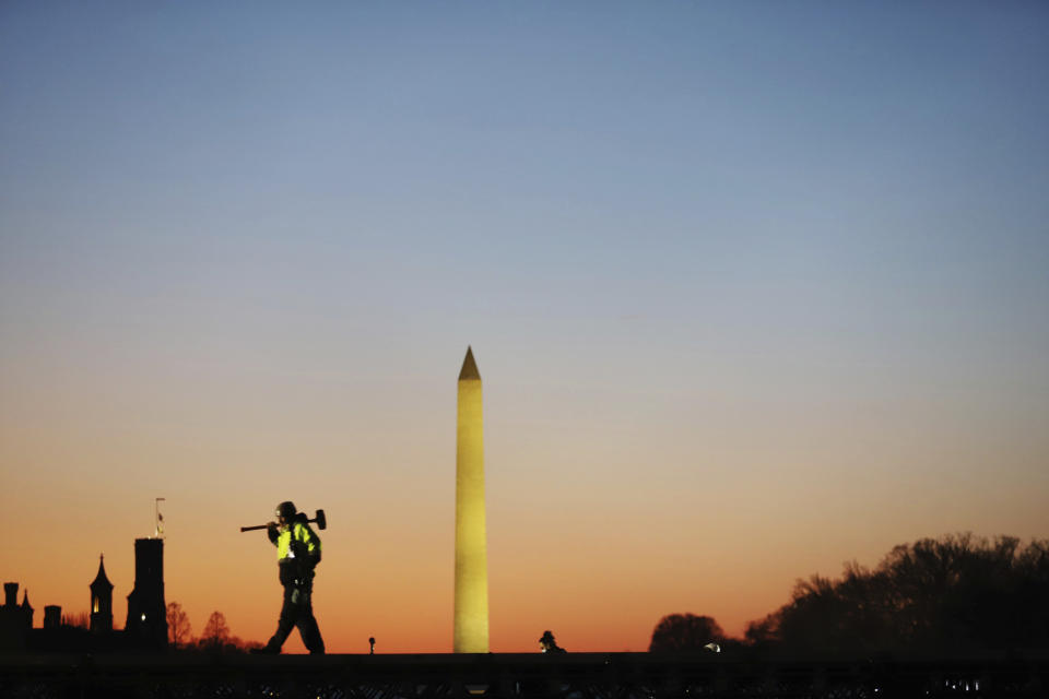 A construction worker carries a hammer on his shoulder on Wednesday, Jan. 13, 2021 at the National Mall in Washington, as a stage is prepared for the 2021 Democrat Joe Biden's presidential inauguration. (AP Photo/Shafkat Anowar)