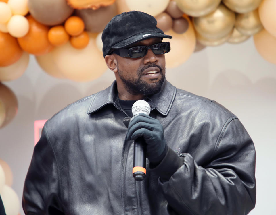 Kanye West speaks while holding a microphone.