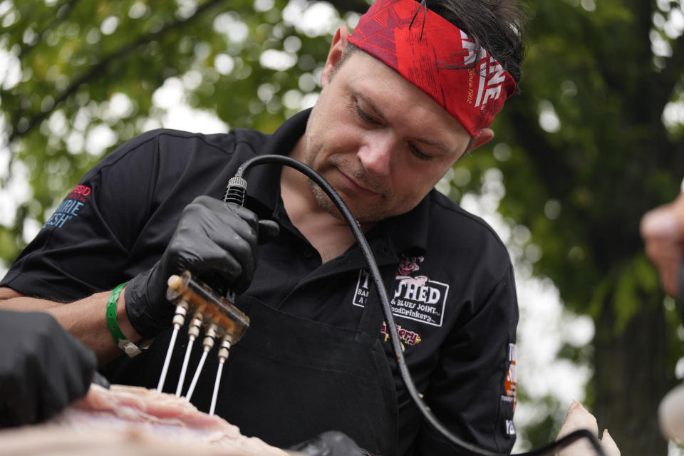 George Logue, pit master for The Shed BBQ and Blues Joint team, injects a whole hog with seasonings at the World Championship Barbecue Cooking Contest, Friday, May 17, 2024, in Memphis, Tenn. (AP Photo/George Walker IV)