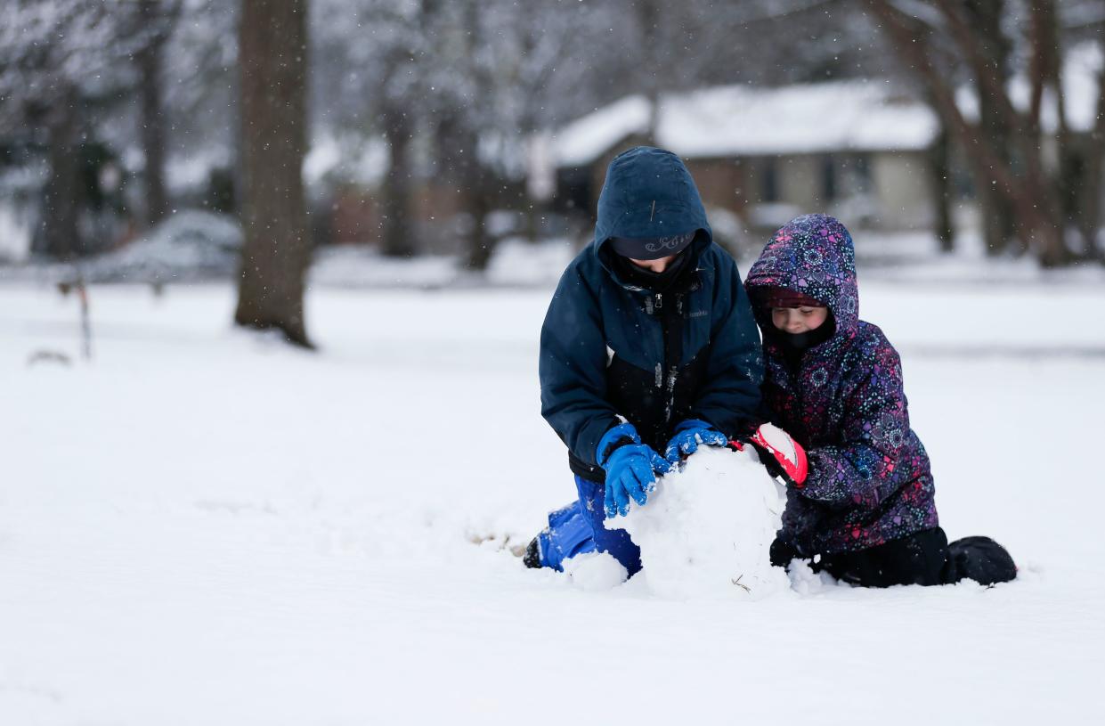 Gregory, 10, and Allison, 7, Soules roll a ball of snow in Phelps Grove Park as they build a snowman on Monday, Feb.12, 2024.