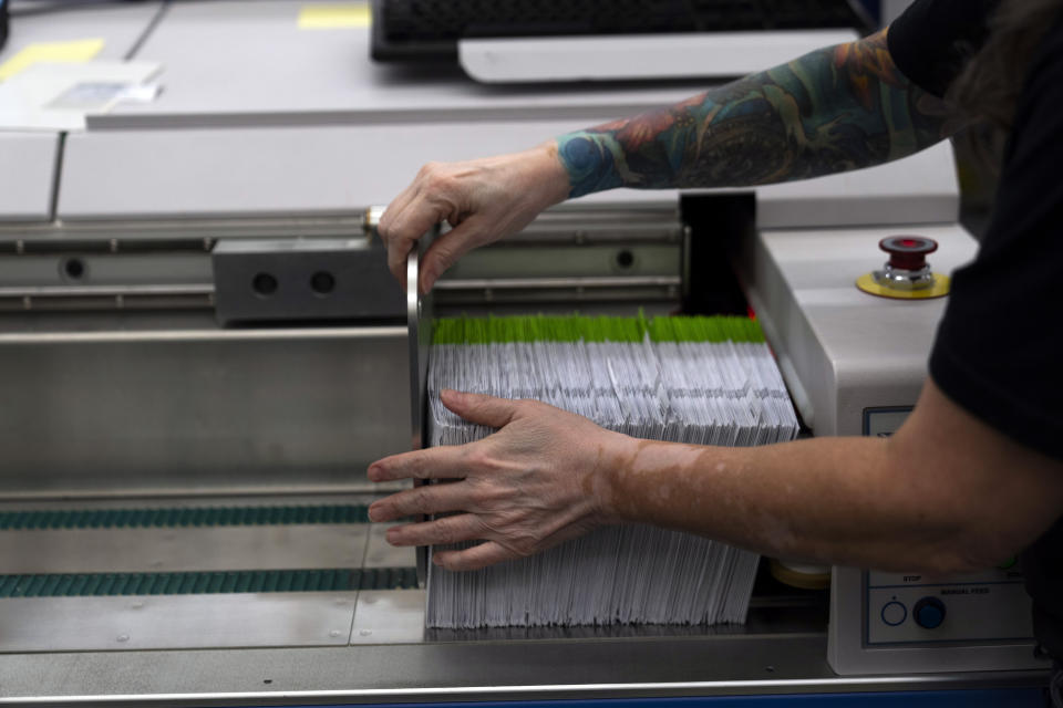 An election worker gathers vote-by-mail ballots for sorting during primary voting at the Multnomah County elections office on Tuesday, May 21, 2024, in Portland, Ore. (AP Photo/Jenny Kane)