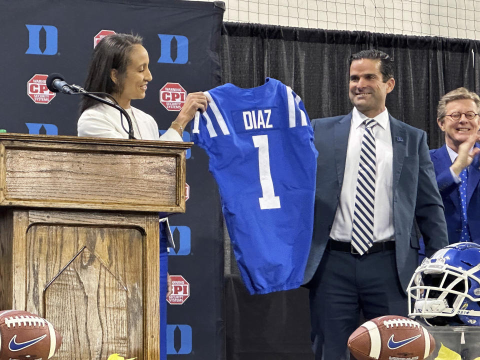 New Duke head football coach Manny Diaz, middle, holds a jersey with Duke Athletic Director Nina King, left, as Duke president Vincent Price looks on, Saturday, Dec. 9, 2023 in Durham, N.C. Duke announced Diaz's hiring on Thursday night, capping a 10-day search after Elko boarded an overnight flight to A&M. (AP Photo/Aaron Beard)