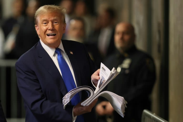 Former US president and Republican presidential candidate Donald Trump holds news clippings as he speaks to the press after the third day of his trial for allegedly covering up hush money payments linked to extramarital affairs at Manhattan Criminal Court in New York on April 18, 2024. A panel of 12 jurors was sworn in on Thursday to sit in judgement of Donald Trump at the unprecedented criminal trial of a former US president. (Brendan McDermid)