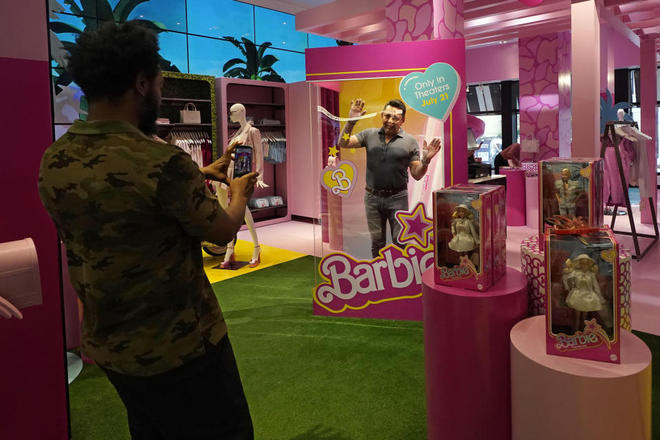 Un hombre posa dentro de una caja de muñeca Barbie en una sección especial con temática de Barbie, en una tienda de la cadena Bloomingdale's en Nueva York, el jueves 20 de julio de 2023. Previo al estreno de la película "Barbie", la empresa matriz Mattel creó un bombardeo de mercadotecnia de productos de más de 100 marcas. (Foto AP/Richard Drew)