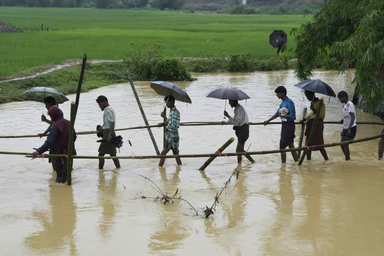 Rohingya Muslim refugees cross floodwater in Thyangkhali refugee camp near the Bangladesh town of Ukhia