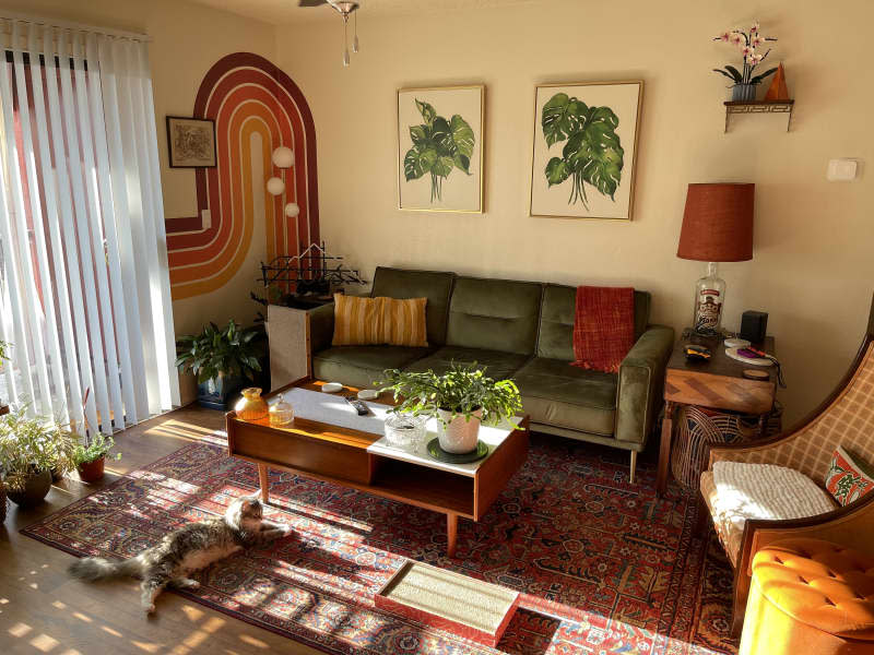 Green velvet couch surrounded by mid-century modern wood side table and coffee table.