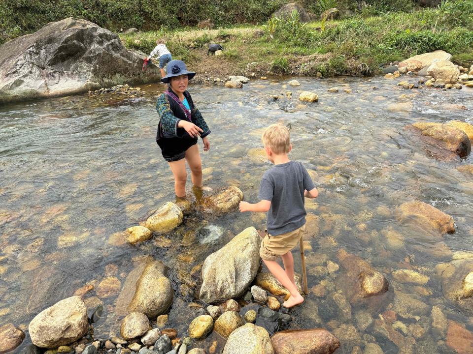 Children and woman crossing river in Sapa, Vietnam