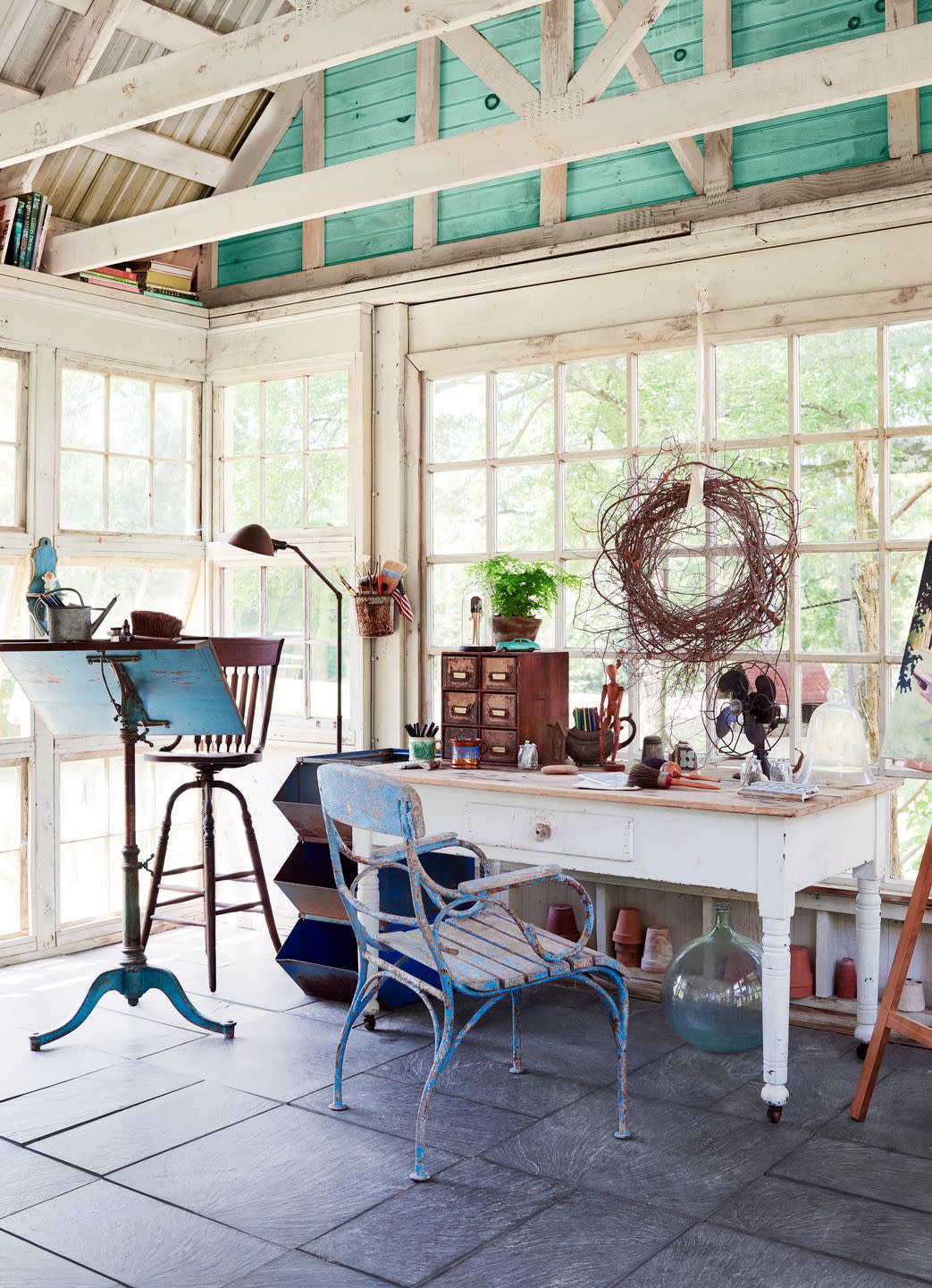 a sunroom with a table, chairs, and art easel