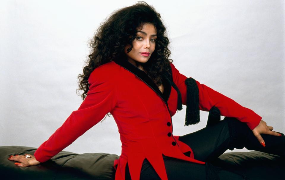 La Toyla Jackson on a couch in a red coat