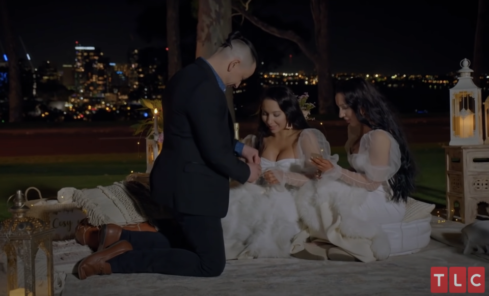 man kneeling with two brides