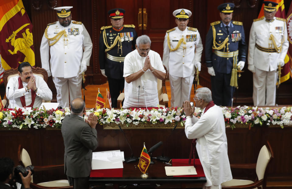 Sri Lankan President Gotabaya Rajapaksa, center, greets his elder brother Chamal Rajapaksa, bottom right, after administering him the oath of office as Agriculture and Trade Minister, watched by Prime Minister Mahinda Rajapaksa in Colombo, Sri Lanka, Friday, Nov. 22, 2019. Gotabaya Rajapaksa, who was elected last week, said he would call a parliamentary election as early as allowed. The parliamentary term ends next August, and the constitution allows the president to dissolve Parliament in March and go for an election. (AP Photo/Eranga Jayawardena)