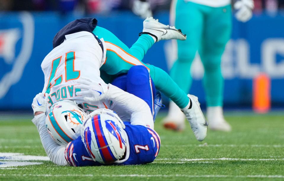 Miami Dolphins wide receiver Jaylen Waddle (17) is tackled by Buffalo Bills cornerback Taron Johnson (7) during the second half in a NFL wild card game at Highmark Stadium.