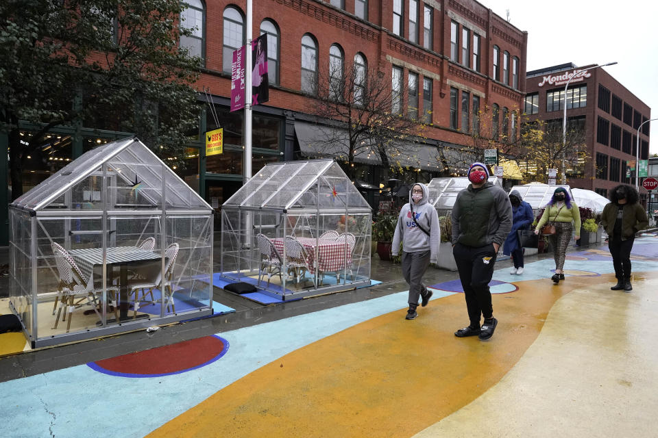 FILE - In this Oct. 18, 2020, file photo, people walk by outdoor plastic dining bubbles on Fulton Market in Chicago. The United States is approaching a record for the number of new daily coronavirus cases in the latest ominous sign about the disease's grip on the nation. (AP Photo/Nam Y. Huh, File)