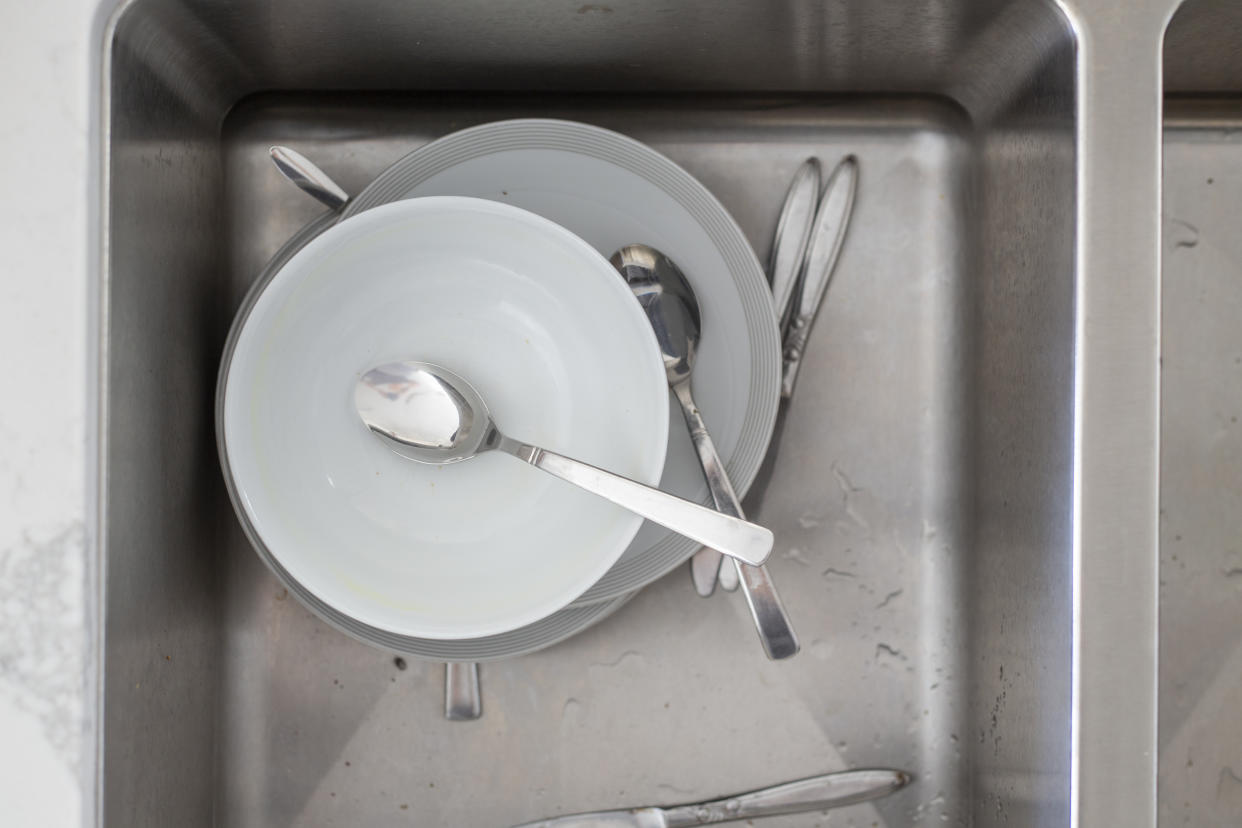 A sink filled with dirty plates, bowls and cutlery.