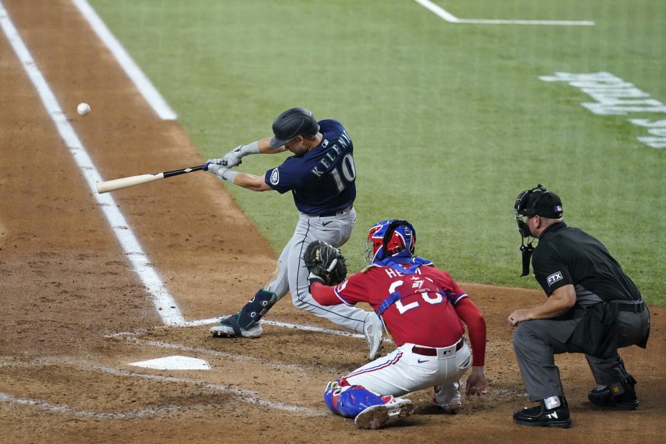 Seattle Mariners' Jarred Kelenic (10) connects for a three-run home run in front ot Texas Rangers' Jonah Heim and umpire Scott Barry during the third inning of a baseball game in Arlington, Texas, Friday, July 30, 2021. (AP Photo/Tony Gutierrez)