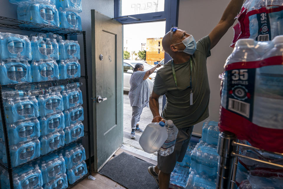 FILE - Chris Cowan with Cascadia Behavioral Healthcare's street outreach team loads water and other cooling supplies before visiting homeless camps on Aug. 12, 2021, in Portland, Ore. Oregon’s most populous county is suing more than a dozen large fossil fuel companies Thursday, June 22, 2023, to recover costs related to extreme weather events linked to climate change. The lawsuit filed in Multnomah County Circuit Court alleges the combined carbon pollution the companies emitted was a substantial factor in causing and exacerbating a 2021 heat dome, which killed 69 people in the county. (AP Photo/Nathan Howard, File)