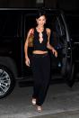 <p>In a black crop top with crystal details, black trousers, a Christian Dior choker, a leopard print handbag with red straps, bedazzled heels, and silver earrings.</p>