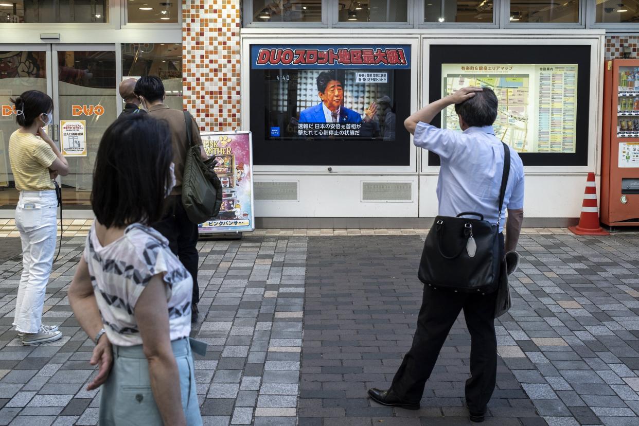 People look at a television broadcasting the news about the attack on former Japanese prime minister Shinzo Abe earlier in the day, along a street of Tokyo on July 8, 2022. 