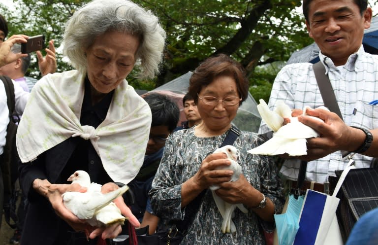 People make a wish as they hold doves before releasing them into the air during a ceremony at controversial Yasukuni shrine