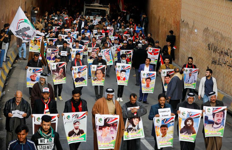 Iraqi demonstrators from Nassiriya city hold the pictures of people who were killed during ongoing anti-government protests in Baghdad