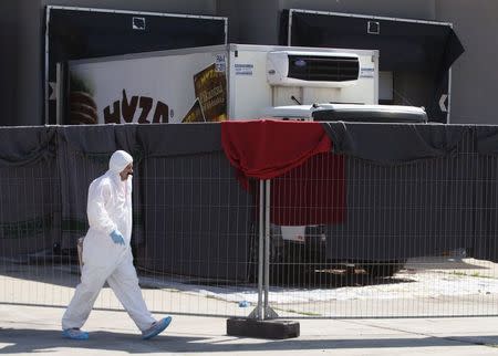 A member of a forensic team walks in front of a truck in which more than 70 bodies were found, at a customs building with refrigeration facilities in the village of Nickelsdorf, Austria, August 29, 2015. REUTERS/Heinz-Peter Bader