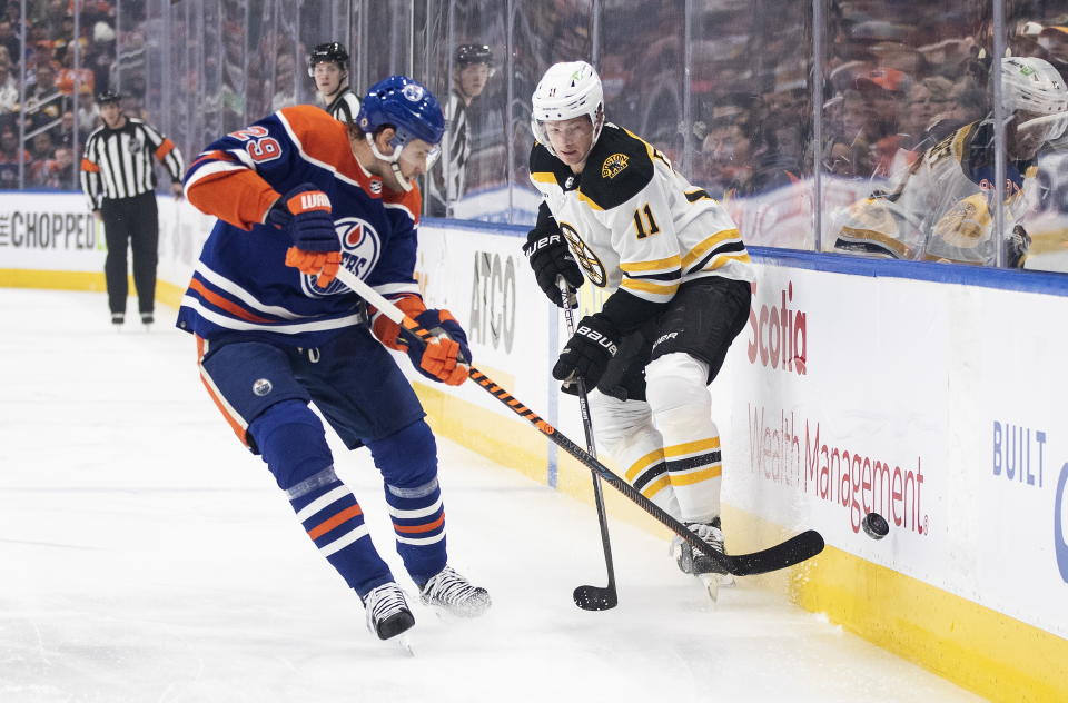 Boston Bruins' Trent Frederic (11) and Edmonton Oilers' Leon Draisaitl (29) battle for the puck during first-period NHL hockey game action in Edmonton, Alberta, Monday, Feb. 27, 2023. (Jason Franson/The Canadian Press via AP)