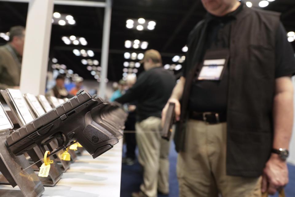 A gun enthusiast looks over the display of pistols in the exhibition hall at the National Rifle Association