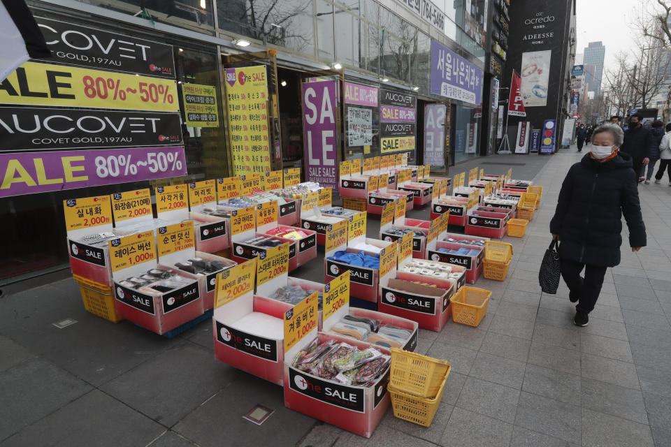 A woman wearing a face mask walks by a merchandise store in Seoul, South Korea, Thursday, March 4, 2021. South Korea's central bank says the country's economy shrank for the first time in 22 years in 2020 as the coronavirus pandemic destroyed service industry jobs and depressed consumer spending. (AP Photo/Ahn Young-joon)