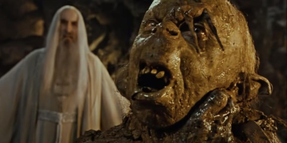 A goblin getting choken with saruman in the background in lord of the rings