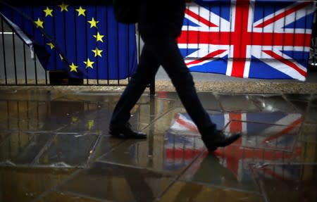 Person walks past an EU and a British flag in London