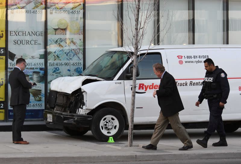 Investigators view a damaged van seized by police after multiple people were struck at a major intersection northern Toronto