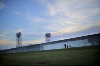 Lower Ninth Ward area residents walk by the reconstructed wall of a levee at the Lower Ninth Ward canal in New Orleans, Louisiana, August 16, 2015. (REUTERS/Carlos Barria)