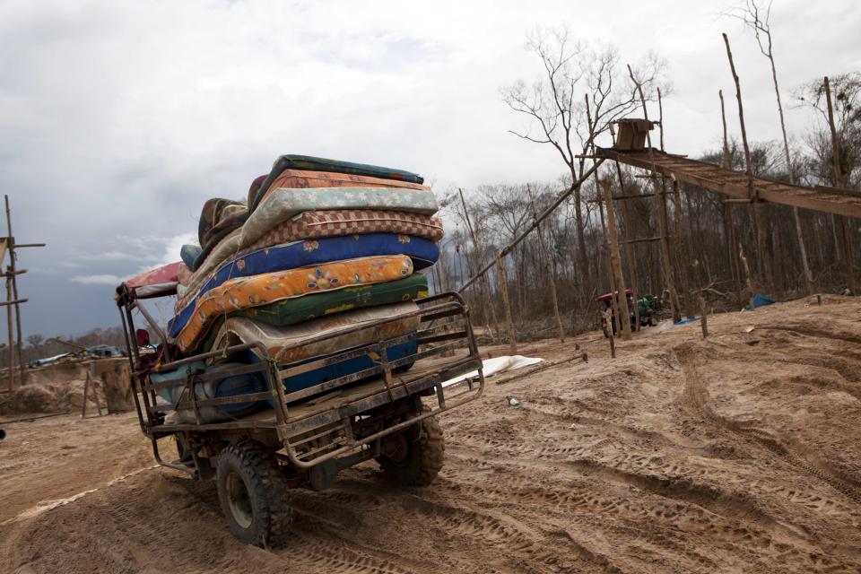 In this May 5, 2014 photo, a motortaxi delivers a cargo of mattresses to a mining camp in La Pampa in Peru's Madre de Dios region. An estimated 20,000 wildcat miners toil in the malarial expanse of denuded rainforest known as La Pampa, an area nearly three times the size of Washington, D.C. (AP Photo/Rodrigo Abd)