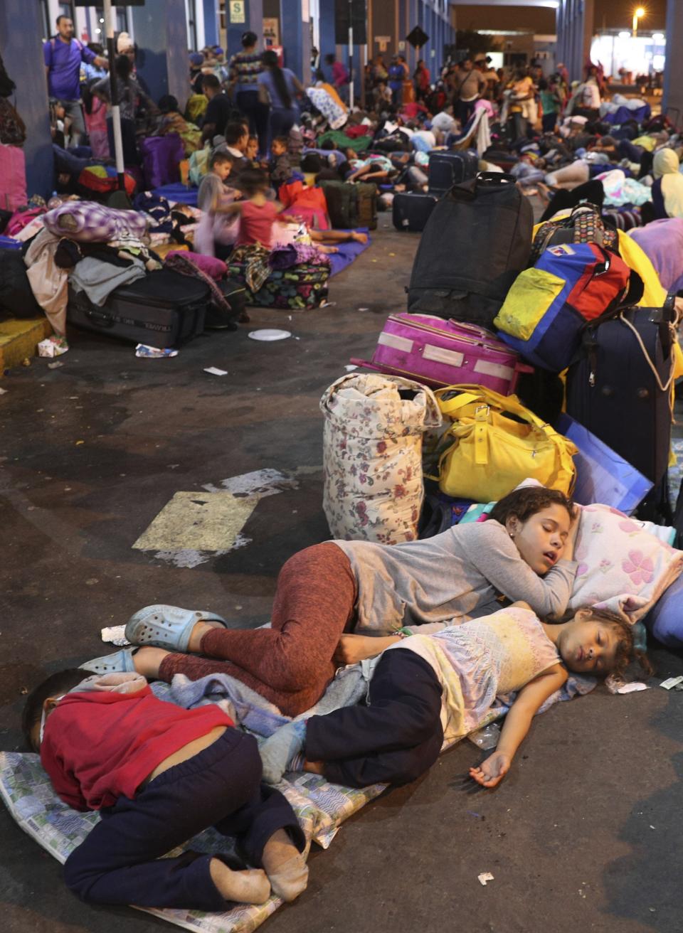 Venezuelan migrant children sleep while waiting with their parents to pass migration controls before the deadline on new regulations that demand passports from migrants, in Tumbes, Peru, Friday, June 14, 2019. Venezuelan citizens are rushing to enter Peru before the implementation of new entry requirements on migrants fleeing the crisis-wracked South American nation. (AP Photo/Martin Mejia)