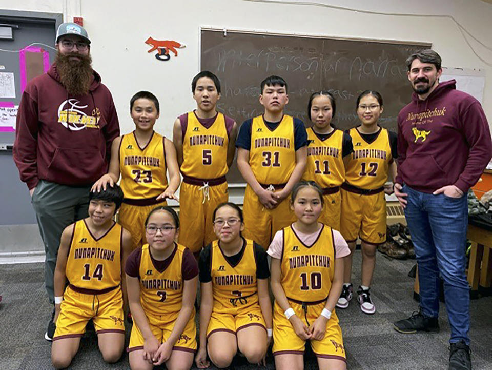 Cory Hughes, back row, right, is pictured with the junior high basketball team he helped coach in Kasigiluk, Alaska, Dec. 16, 2022. Hughes, dean of students in Nunapitchuk, Alaska, said he loves his community and wants to stay there but said the retirement system currently available for teachers in Alaska makes the idea of retiring in the rural community nearly impossible. (Bo Sahr via AP)