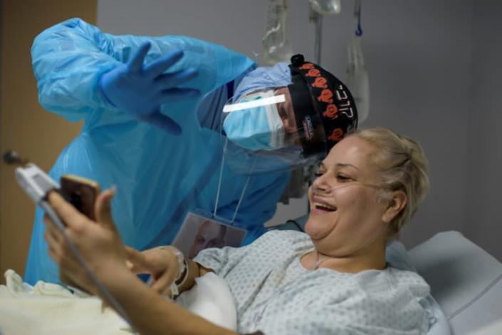 Chief of Staff Joseph Varon smiles and waves to Gloria Garcia's family as she video calls them from the Covid-19 ward at United Memorial Medical Center in Houston, Texas on December 4, 2020