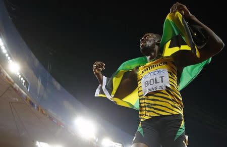 Usain Bolt of Jamaica celebrates with his national flag after winning the men's 200 metres final during the 15th IAAF World Championships at the National Stadium in Beijing, China, August 27, 2015. REUTERS/Kai Pfaffenbach