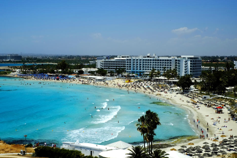 A view of the famous Nissi Beach with people as they enjoy the beach and the sea in southeast resort of Ayia Napa, in the eastern Mediterranean island of Cyprus, Saturday, May 22, 2021. Cypriot hotel and other tourism-related business owners say they'd like to see the COVID-19 pandemic-induced uncertainty over travel bookings to the tourism-reliant island nation winding down by July when they're hoping authorities in Cyprus' main markets including the U.K., Russia, Germany and the Scandinavian countries will make it easier for their citizens to travel abroad. (AP Photo/Petros Karadjias)