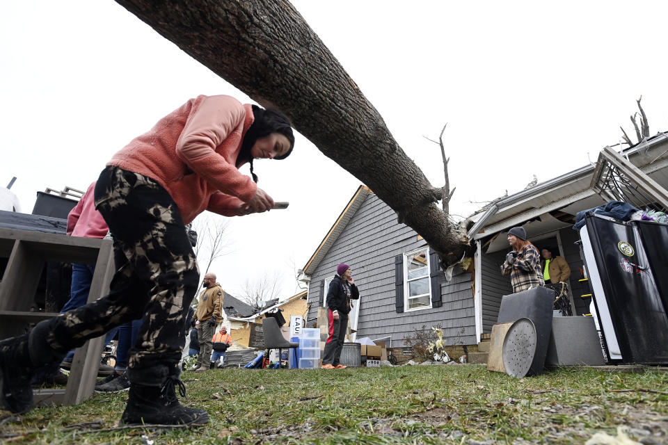 Amber Davidson ducks under the tree that hit her house, Sunday, Dec. 10, 2023, in Clarksville, Tenn. Tornados caused catastrophic damage in Middle Tennessee on Saturday afternoon and evening, Dec. 9. (AP Photo/Mark Zaleski)