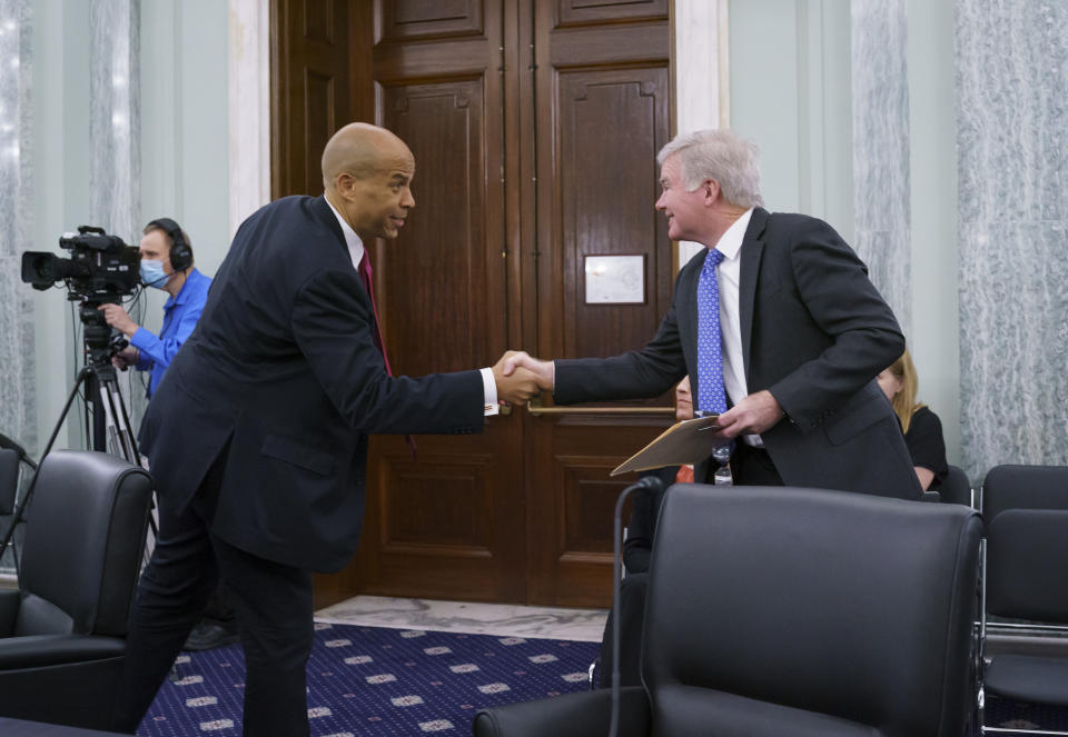 Sen. Cory Booker, D-N.J., left, greets NCAA President Mark Emmert, as the Senate Commerce, Science, and Transportation Committee holds a hearing on student athlete compensation and federal legislative proposals to enable athletes participating in collegiate sports to monetize their name, image, and likeness, at the Capitol in Washington, Wednesday, June 9, 2021. (AP Photo/J. Scott Applewhite)