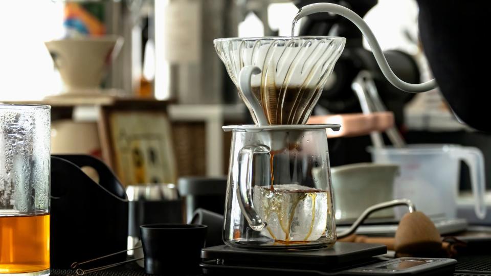 A pour over coffee maker brewing coffee on a busy cafe countertop