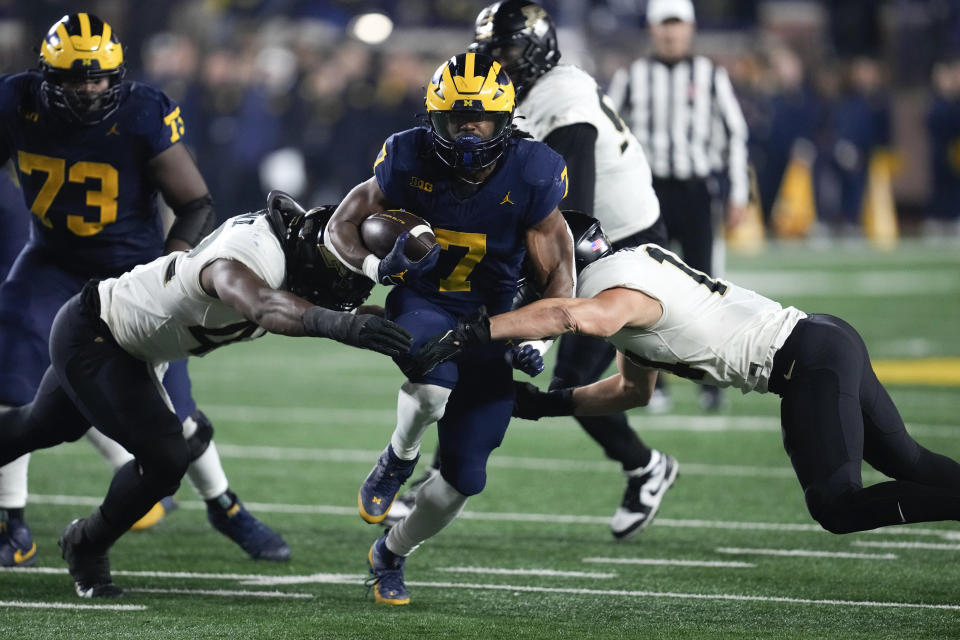 Michigan running back Donovan Edwards (7) runs the ball as Purdue linebacker Clyde Washington, left, and Yanni Karlaftis (14) converge for the stop in the second half of an NCAA college football game in Ann Arbor, Mich., Saturday, Nov. 4, 2023. (AP Photo/Paul Sancya)