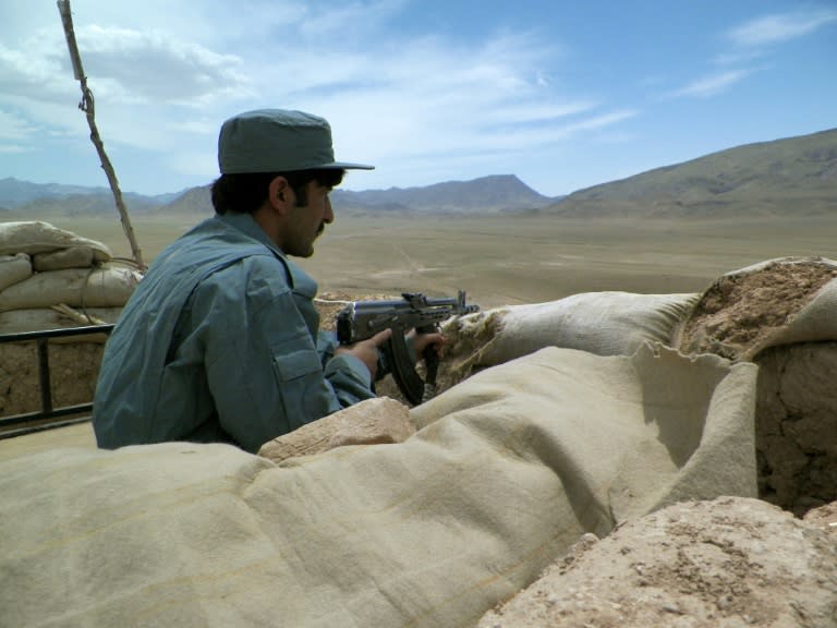 An Afghan policeman keeps watch from a checkpoint on the Kandahar-Tarin Kot highway