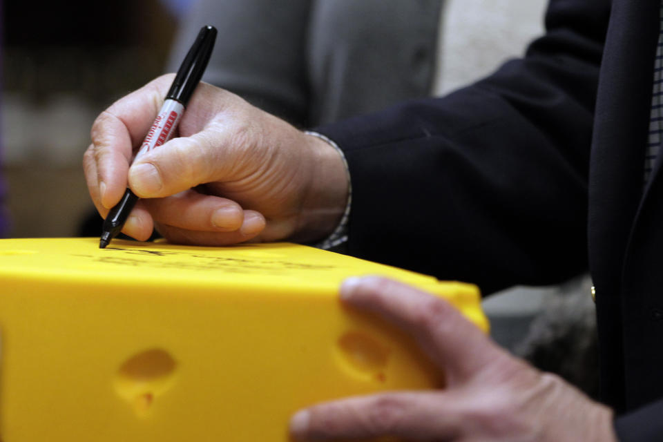 Republican presidential candidate, former Pennsylvania Sen. Rick Santorum signs his autograph on a cheese head hat at Simon's Specialty Cheese in Appleton, Wis., Monday, April 2, 2012. (AP Photo/Jae C. Hong)