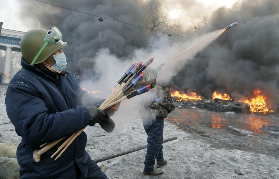 FILE In this file photo taken on Thursday, Jan. 23, 2014, A protester aims fireworks at police during clashes, in central Kiev, Ukraine. Thick black smoke from burning tires engulfed parts of downtown Kiev as an ultimatum issued by the opposition to the president to call early elections or face street rage was set to expire with no sign of a compromise on Thursday. (AP Photo/Efrem Lukatsky, file)