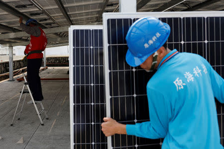 A prisoner (L) places solar panels on the roof of Pingtung Prison in Pingtung, Taiwan February 15, 2017. REUTERS/Tyrone Siu