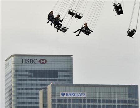 Financial offices of Canary Wharf are seen behind visitors to the O2 arena enjoying a fairground ride in east London November 23, 2011. REUTERS/Toby Melville