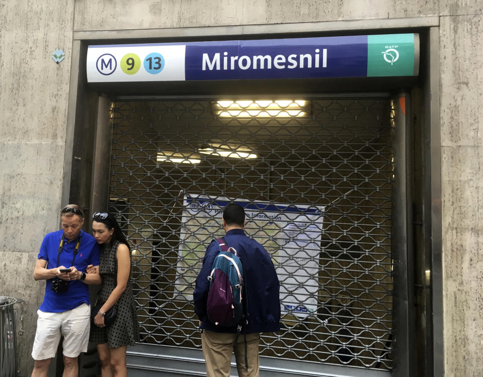 People stand by a closed metro station Friday Sept.13, 2019 in Paris. A massive strike is paralyzing Paris public transports on Friday as unions protest a sweeping pension reform by French President Emmanuel Macron's government. Paris public transport company RATP says 10 metro lines are closed and several others, including the RER suburban rail, are severely disrupted. (AP Photo/Bertrand Combaldieu)